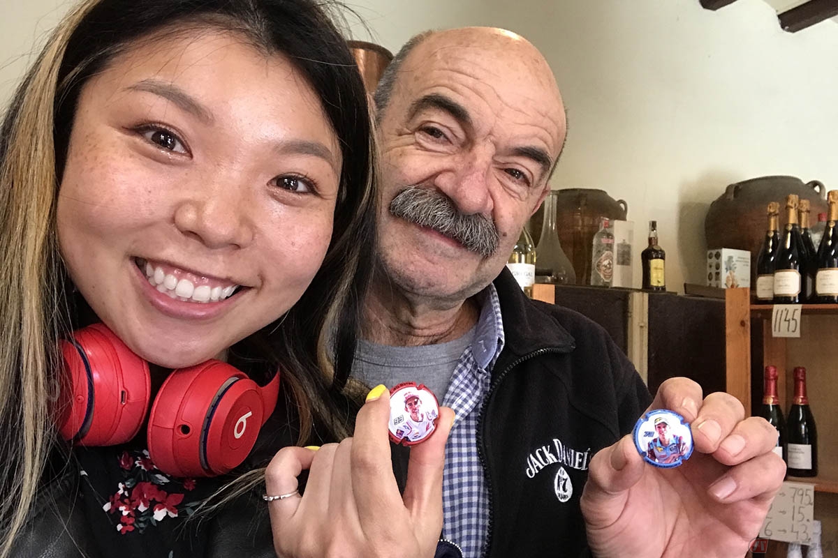 マルク・マルケス選手の地元「Cervera（サルベラ）」の酒屋“Vins I Licors Carbonell”を訪れた岸田彩美さん。亭主のハビエルさんからプレゼントしてもらったオリジナルボトルキャップにご満悦です