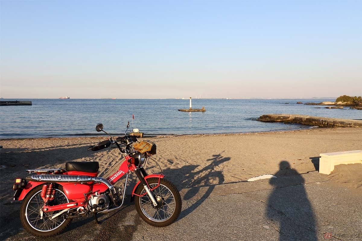 浦賀水道を背景に筆者(増井貴光)のホンダ「CT110」を撮影。影が写り込んでいるのは自己主張