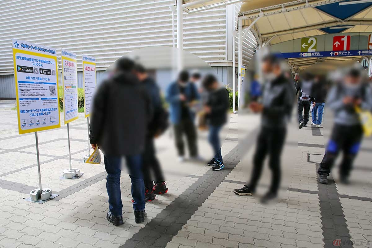 入口では連絡先の登録や新型コロナ接触通報アプリCOCOAのダウンロードが推奨され、スマホを操作する来場者が立ち止まっていた（大阪）