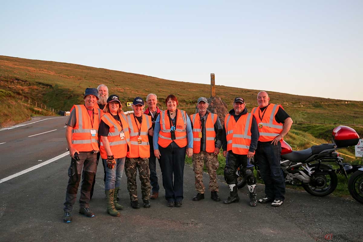 TTマウンテンコースのギャスリーズ・メモリアルを担当するマーシャルたち。地元マン島在住の人もいれば、イギリスやアイルランドなど海外からやってきてボランティア活動をする人も多い。視認性の高いオレンジ色のベストを着用することになっていることから「オレンジ・アーミー」とも呼ばれる（写真／小林ゆき）