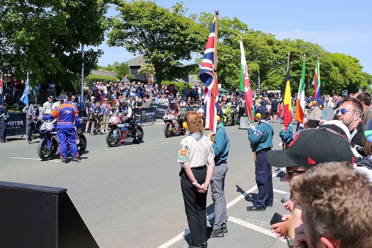 スタートのグリッドに並ぶ選手と、それを彩る国旗を掲げたスカウト隊の子どもたち