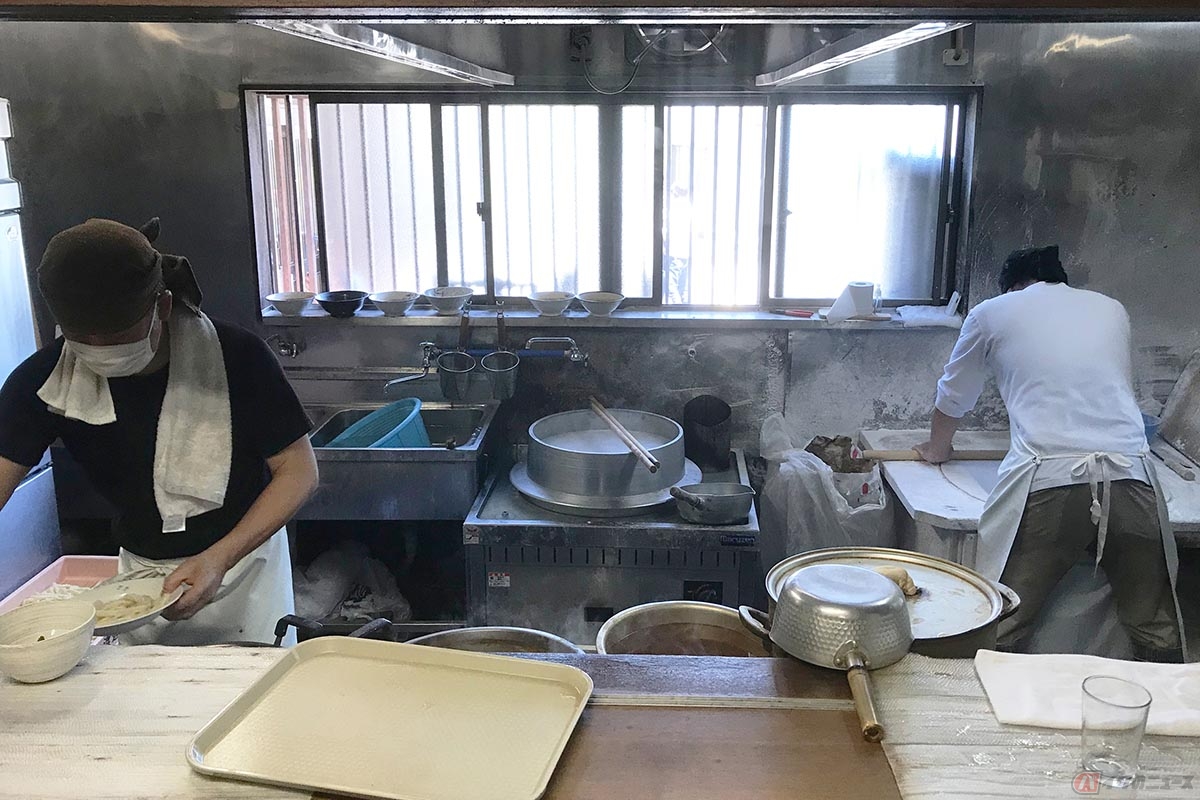 男性が力強く生地を伸ばしています。中央には大きな釜も見えます