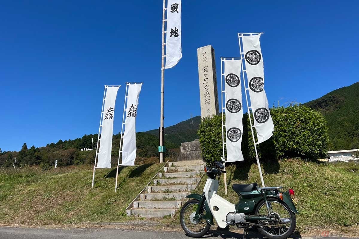 「関ケ原の戦い」の舞台の象徴でもある「決戦地」をスーパーカブで訪れた。石碑の背後には石田隊が陣を構えた笹尾山が見える