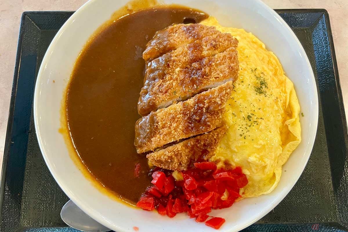 関越道「三芳PA」(下り)でいただく「オムカツカレー」(1130円)は、俯瞰で眺めるとカレーソースの水面とフワトロ玉子の輝きが美しさを放つ。カツにはウスターソースを少々