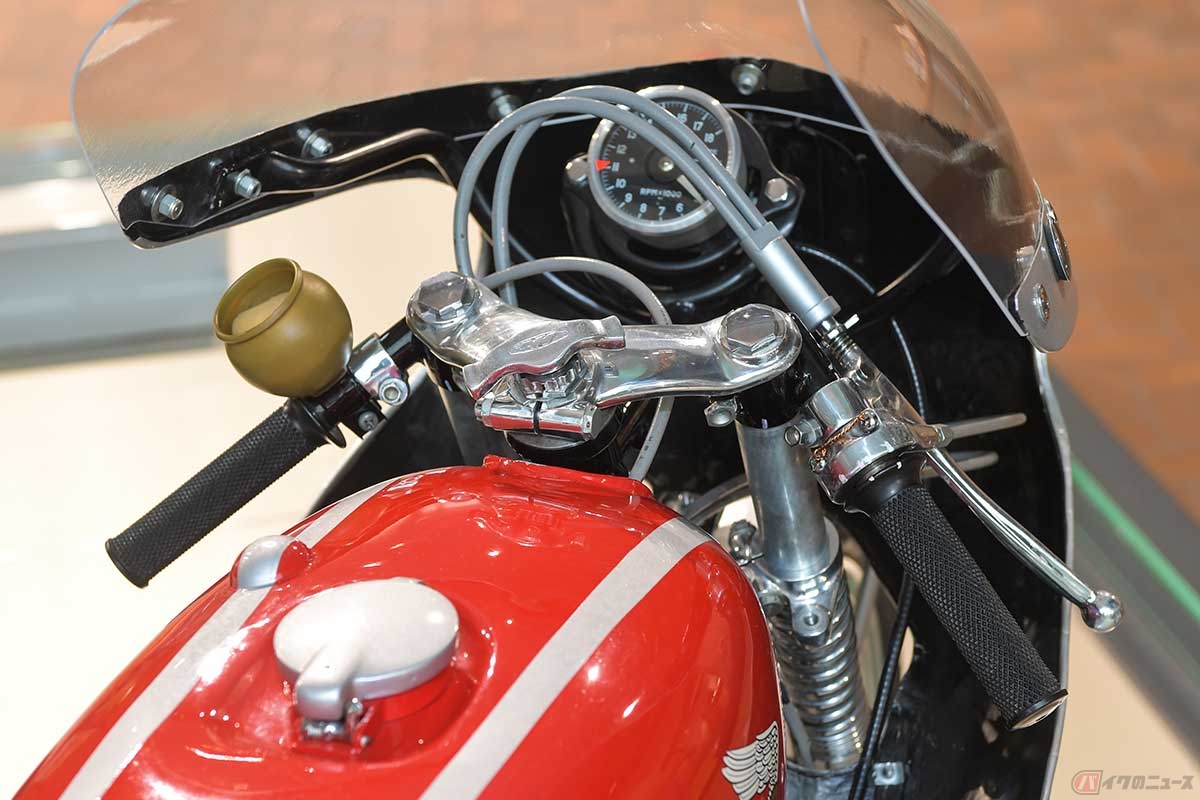 「RC143」のハンドルまわり。左手側にはゴーグルに付いた虫をぬぐい取るためのスポンジ入れ、中央にはステアリングダンパーの調整ノブが見られる