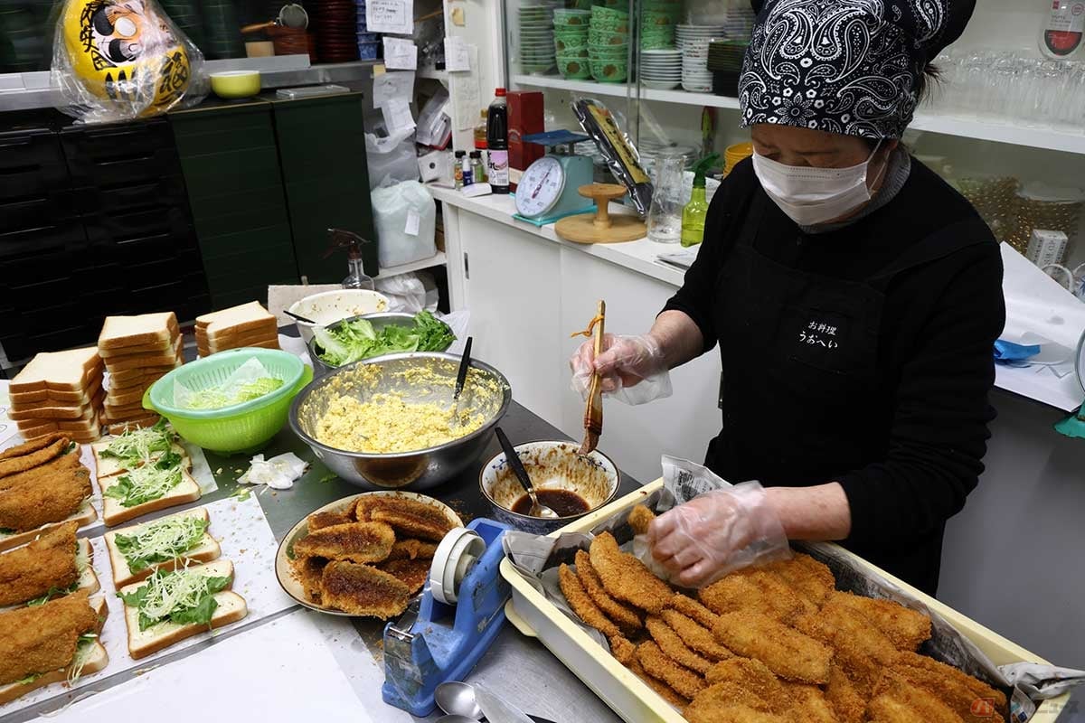 「FLAT FISH」の「アジフライサンド」を料理中。アジフライは大きめの生のアジを半身にして揚げている。この日は100個を販売した