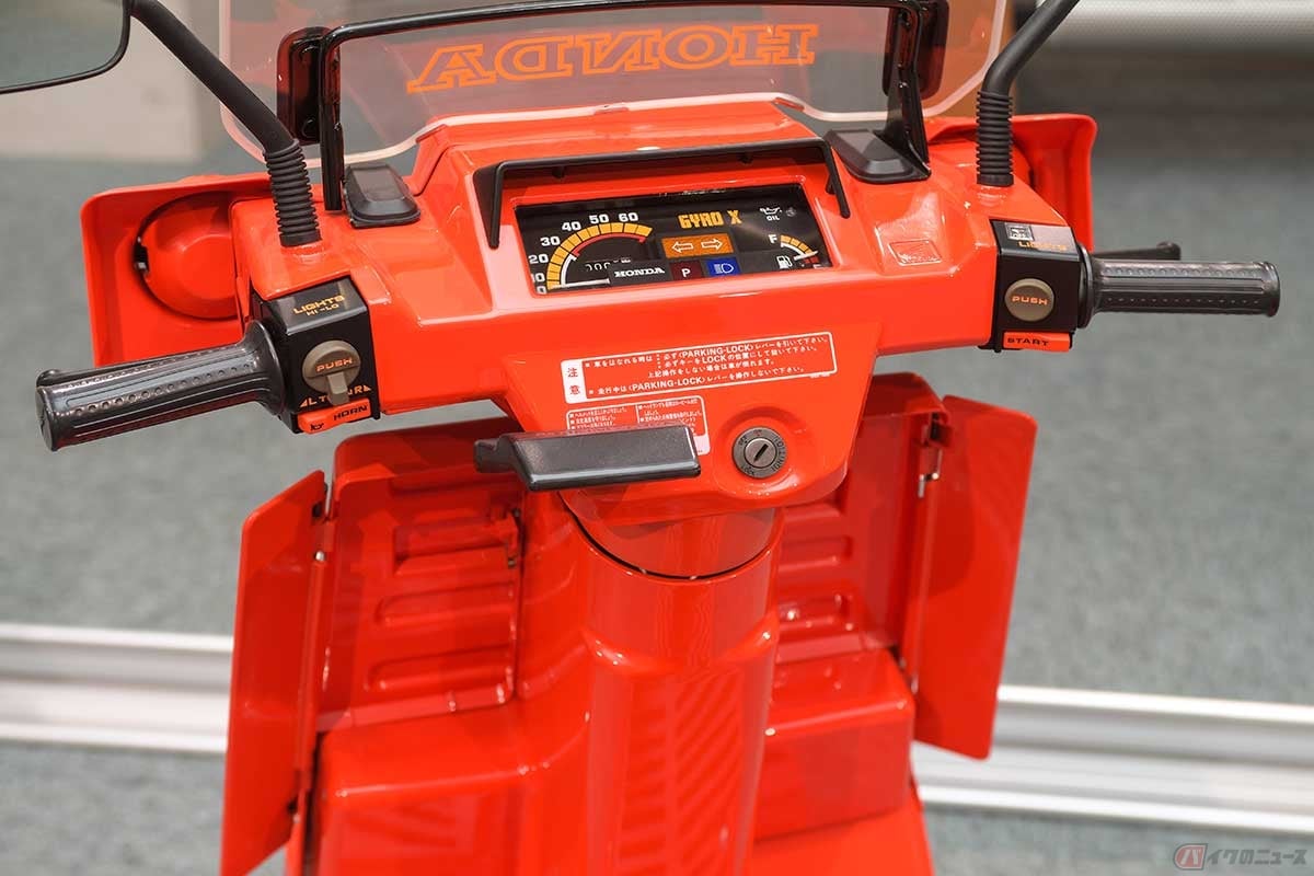 燃料系も備えたスピードメーターの下に、ワンタッチパーキングレバーを配置。レッグシールド部には左右に開閉可能なウイングバイザーを備え、雨や泥しぶきからライダーの足元を守る