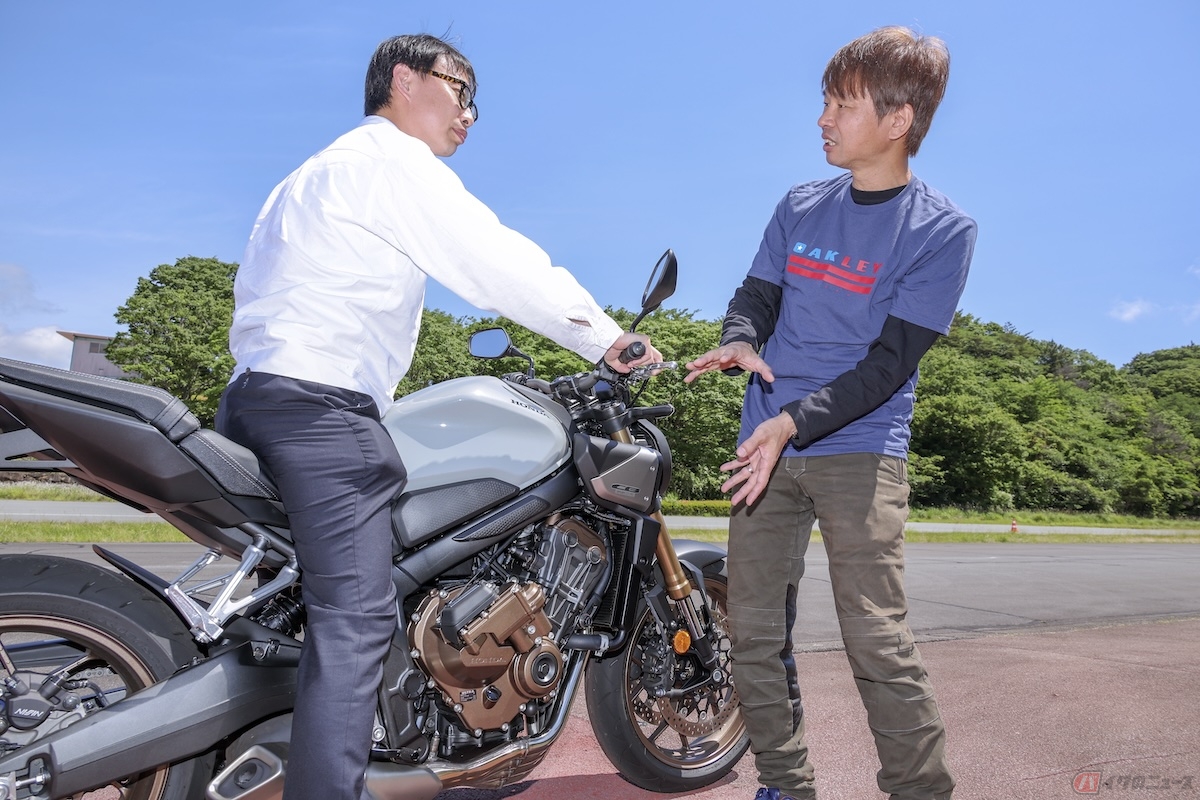 ホンダEクラッチ開発責任者の小野惇也さん(二輪・パワープロダクツ事業本部二輪パワープロダクツ開発生産統括部完成車開発部)に操作方法を詳しく聞く筆者(青木タカオ)