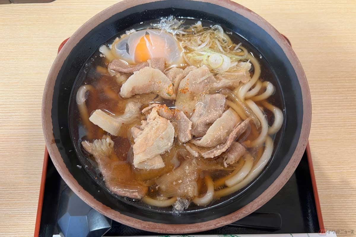 東名高速「港北PA」(上り)で柔らかく煮込まれた豚肉がどっさりと入った温かい「自家製肉うどん」(690円)を実食。生玉子をトッピングし、七味を少々ふりかけていただいた