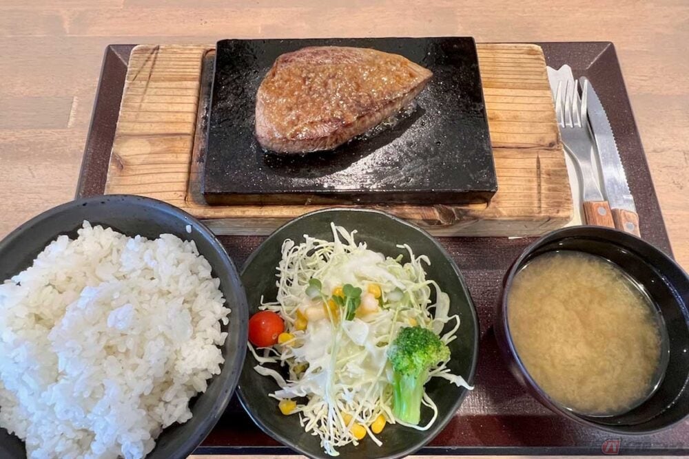 東名高速「駒門PA」(下り)で見つけた「溶岩焼き ランプステーキ」(1300円)は、富士山の溶岩プレートで焼き上げる、いつまでも熱々のステーキ。ご飯は無料で大盛りに。サラダや味噌汁もセットでこの値段はコスパが高い。分厚いプレートはかなり重く、慎重にトレーを運んだ