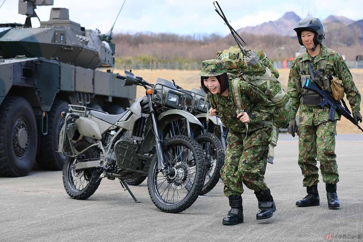 陸上自衛隊の相馬原駐屯地の第12偵察戦闘大隊、偵察中隊のオートバイ部隊の隊員が携帯する荷物を背負ってみる夜道雪さん。その重さにビックリ!!