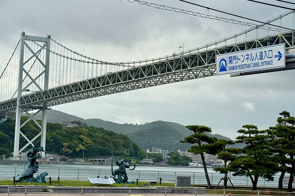 源平合戦「壇ノ浦の戦い」のモニュメントの上にかかる関門橋。向こうには関門海峡と、対岸の福岡県門司の陸地が見えます