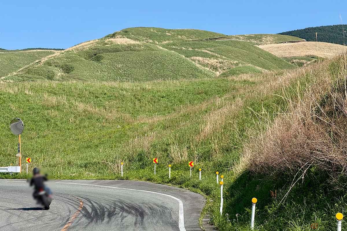 「俵山峠」山頂を目指すヒルクライムルート。阿蘇らしい草原地帯を走る。遠く高くにはこの先に登る道のガードレールが見えています
