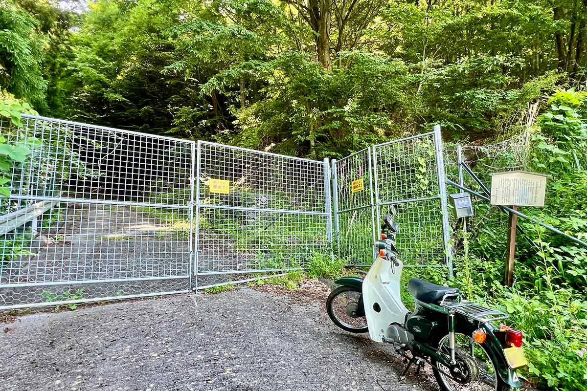 「桐原城跡」の入口には解説板と鳥獣避けフェンスがある。バイクを道の脇に停めて散策