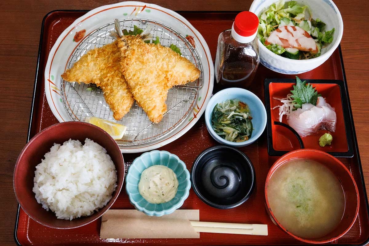 「市場の食堂　金目亭」の「アジフライ定食（刺身1点付）」は、アジフライに刺身やサラダ、小鉢が並ぶボリュームがあって嬉しい定食