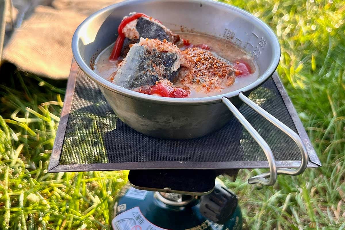 具材をシェラカップに投入してバーナーで加熱する。缶を直接火にかけるより器に移す方が安心